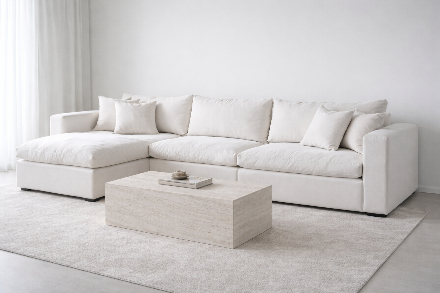 White modular feather cloud sectional sofa in a minimalistic living room with a travertine coffee table.